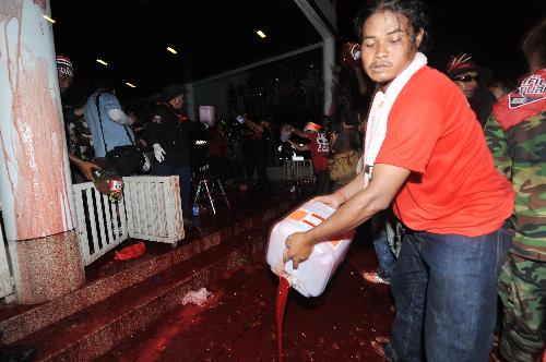 A Thai red-shirted demonstrator pours blood on the footpath in front of the ruling Democrat Party&apos;s headquarters in Bangkok, capital of Thailand, March 16, 2010. The Thai anti-government group here on Tuesday poured the blood donated earlier the day by the &apos;red-shirts&apos;, who are staging a mass rally in an effort to topple the government. [Lui Siu Wai/Xinhua] 