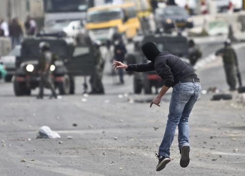 A Palestinian protester hurls stones at Israeli soldiers during clashes at Qalandiya checkpoint near the West Bank city of Ramallah on March 17, 2010. Clashes erupted to protest against Israeli consecrating a synagogue in the old city of Jerusalem. [Fadi Arouri/Xinhua] 