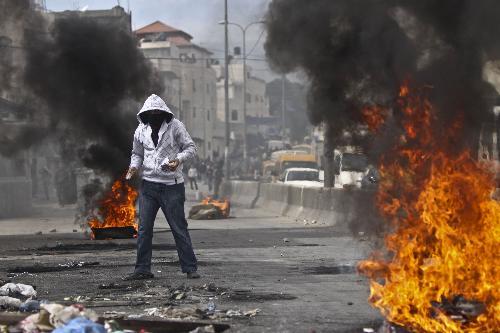 A Palestinian protester hurls stones at Israeli soldiers during clashes at Qalandiya checkpoint near the West Bank city of Ramallah on March 17, 2010. Clashes erupted to protest against Israeli consecrating a synagogue in the old city of Jerusalem. .[Mamoun Wazwaz/Xinhua] 