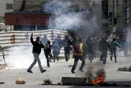 Palestinian protesters run to take cover during clashes with Israeli soldiers in the West Bank city of Hebron on March 17, 2010. Clashes erupted to protest against Israeli consecrating a synagogue in the old city of Jerusalem. [Mamoun Wazwaz/Xinhua] 