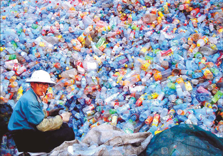 A man sorts empty plastics bottles into different categories at a garbage recycling plant in the suburbs of Huaibei, a city in Anhui province. China consumes 52 million tons of plastics a year. [China Daily]