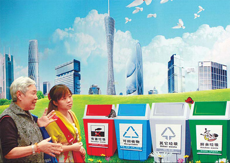Two residents in Guangzhou, Guangdong province, walk beside an advertisement promoting sorting waste on Sunday. [China Daily]