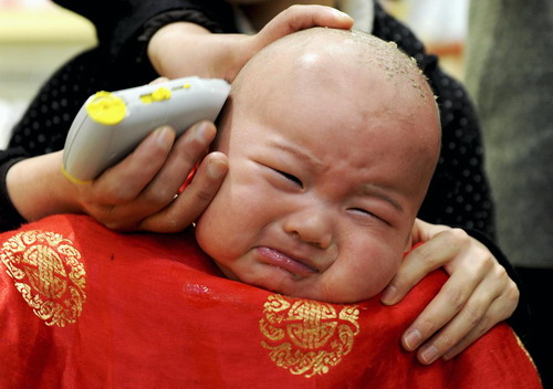 A child gets a haircut at a barbershop in Hefei, Anhui province March 17, 2010. 
