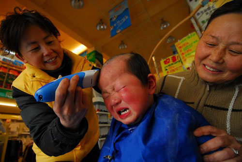 A child gets a haircut at an infant barbershop in Hefei, capital of east China's Anhui province, on Wednesday, March 17, 2010.