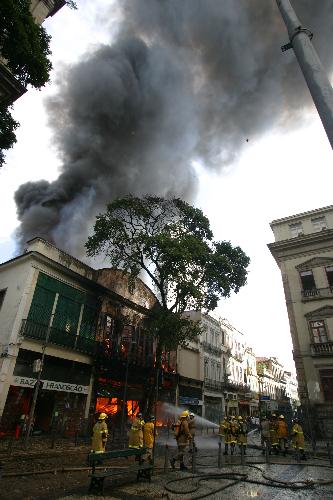 Firefighters try to extinguish the fire of a building in the center of Rio de Janeiro, Brazil, March 18, 2010. After two hours&apos; working, firefighters controlled the fire.[Agencia Estado/Xinhua]