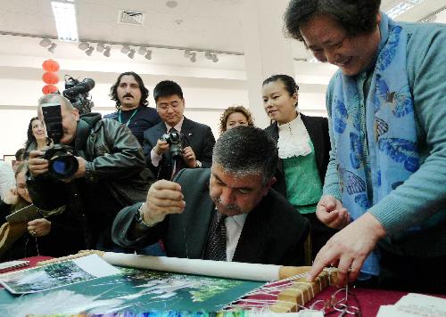 Ismet Yilmaz, undersecretary of Turkish Culture and Tourism Ministry, tries the embroidery during an exhibition on China's Suzhou embroidery in Ankara, capital of Turkey, March 18, 2010. Some 60 pieces of Suzhou embroidery works were on show during the exhibition. [Wang Xiuqiong/Xinhua]