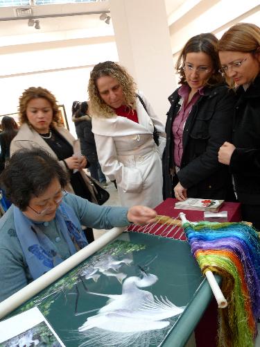 People watch a Chinese craftswoman embroidering during an exhibition on China's Suzhou embroidery in Ankara, capital of Turkey, March 18, 2010. Some 60 pieces of Suzhou embroidery works were on show during the exhibition. [Wang Xiuqiong/Xinhua]