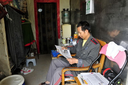 A security guard reads the newspaper in his container house near the 107 National Highway, Xinwu Street, Shenzhen Bao'an District, on March, 17, 2010