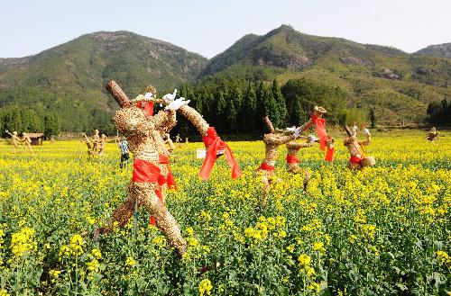 Straw men are seen in the cole field at the Shenxianju scenic area in Taizhou City, east China's Zhejiang Province, March 18, 2010. Some 100 straw men are placed in the fields to decorate the coming local cole flower festival.