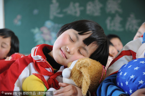 A girl holds her pet toy while practicing sleeping during a special 'sleep class' ahead of the World Sleep Day at a primary school in Nanyang city, Henan province. Students were taught different ways to improve their sleep. Started by the International Foundation for Mental Health and Neuro-Science in 2001 to raise awareness of sleeping disorders, the World Sleep Day falls on March 21 every year.