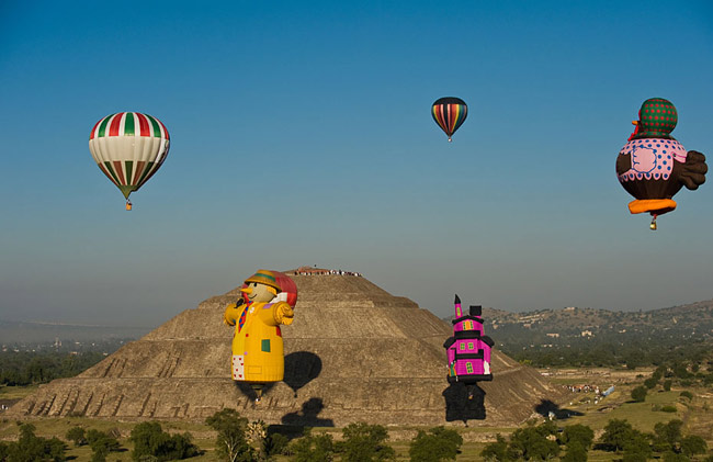 Hot air balloons float past people watching the sunrise at the Sun pyramids of Teotihuacan during a festival as part of the spring equinox outside Mexico City March 21, 2010. Hundreds of Mexicans and tourists gather at Teotihuacan every year to welcome spring equinox at the Pyramid of the Sun. [Xinhua/Reuter]