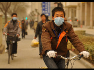 A man wearing a mask rides a bike in sand-dust weather in Beijing, capital of China, March 22, 2010. The Central Meteorological Station issued a blue alert for sandstorms at 6 AM on Monday. [Xinhua]