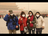 Tourists visit the Tian'anmen Square in sand-dust weather in Beijing, capital of China, March 22, 2010. The Central Meteorological Station issued a blue alert for sandstorms at 6 AM on Monday. [Xinhua]