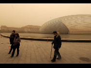 Tourists visit the National Centre for the Performing Arts in sand-dust weather in Beijing, capital of China, March 22, 2010. The Central Meteorological Station issued a blue alert for sandstorms at 6 AM on Monday. [Xinhua]