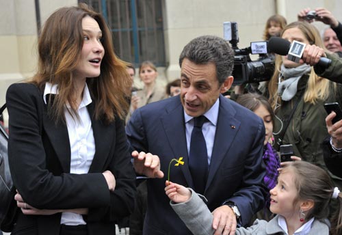 A young girl offers a flower to France's President Nicolas Sarkozy (C) and his wife Carla Bruni-Sarkozy (L) as they leave a Paris polling station after voting in the second round of regional elections March 21, 2010. Sarkozy's centre-right UMP party is due to face heavy losses in regional elections on Sunday that could affect the pace of reform as manoeuvring begins before the 2012 presidential campaign.[Xinhua]