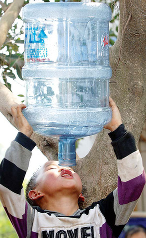 A boy squeezes the last drop from a mineral water bottle in Wulong county, Chongqing, on Saturday. The area is suffering from one of the severest droughts in history. [Xinhua] 