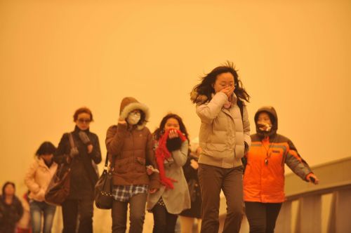 People walk on a street in Beijing, capital of China, March 20, 2010. A severe sandstorm that plagued northwestern China in the past few weeks arrived in Beijing Friday night, packing strong winds and tones of sand. [Xinhua]