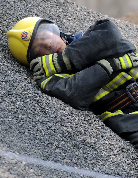 A rescuer rest on the floor during a break while rescue efforts are going on for ten workers who were trapped in a collapsed railway tunnel in north China's Inner Mongolia autonomous region, Sunday, March 21, 2010. 