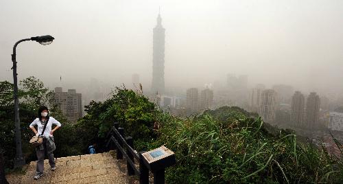 A girl wearing a mask takes a break on a path up to a hill amid a floating dust weather in downtown Taipei, southeast China's Taiwan, March 21, 2010. A sandstorm hit the island on Sunday. (Xinhua/Wu Ching-teng