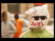 A pedestrian covers his face with a plastic bag against the sandstorm on March 22, 2010 in Beijing, China. Tons of sand carried by winds of up to 100 km/h has affected more than 270 million people in 16 provinces since Friday, covering about 2 million sq km. [Chinanews.com.cn]
