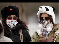 Pedestrians cover their face against the sandstorm on March 20, 2010 in Beijing, China. [Chinanews.com.cn]