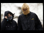 Pedestrians cover their face against the sandstorm on March 20, 2010 in Beijing, China. [Chinanews.com.cn]