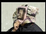 A pedestrian covers his face against the sandstorm on March 20, 2010 in Beijing, China. [Chinanews.com.cn]