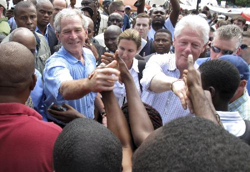 Former U.S. presidents George W. Bush (L) and Bill Clinton shake hands with earthquake survivors during a visit to Champ Mars near the national palace in Port-au-Prince March 22, 2010. Clinton and Bush are in Haiti to discuss the impoverished country's long-term recovery after a January earthquake killed hundreds of thousands of people. [Xinhua]