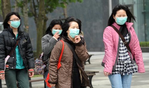 Local citizens wearing masks walk ahead against floating dust on the street in downtown Taipei, southeast China&apos;s Taiwan, March 21, 2010. A sandstorm hit the island on Sunday. [Xinhua]
