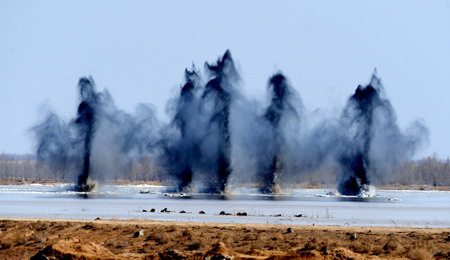 The explosions are seen as they break the ice of the dangerous Minjibu Reach of the Yellow River under the bombardment in Tumd Right Banner of north China's Inner Mongolia Autonomous Region on March 22, 2010. The 1.5-meter-high ice dam filling up in the riverway was scrapped to meet the extensive ice run.[Xinhua]