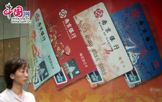 A pedastrian walking past an outdoor commercial of Bank of Nanjing's bank cards. [CFP]