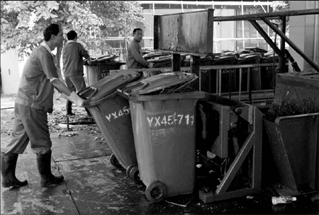 Workers organize garbage bins in Guangzhou's first kitchen waste treatment plant. [China Daily]