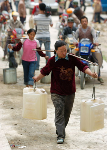  People carry drinking water at a water supply point of Wenqian village at Dongshan Township in Bama Yao Autonomous County, southwest China&apos;s Guangxi Zhuang Autonomous Region, March 23, 2010. Thirteen of total fourteen cities in Guangxi have been suffered with severe drought, and 7.82 million people are affected by the drought, according to local bureau of civil affairs. [Xinhua]