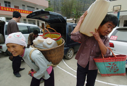 People carry drinking water at a water supply point of Wenqian village at Dongshan Township in Bama Yao Autonomous County, southwest China&apos;s Guangxi Zhuang Autonomous Region, March 23, 2010. Thirteen of total fourteen cities in Guangxi have been suffered with severe drought, and 7.82 million people are affected by the drought, according to local bureau of civil affairs. [Xinhua]