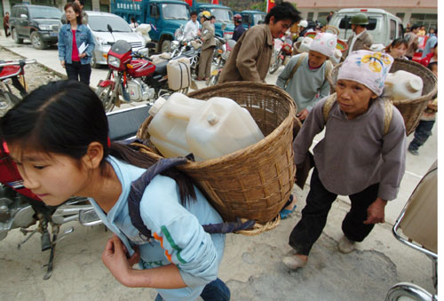 People carry drinking water at a water supply point of Wenqian village at Dongshan Township in Bama Yao Autonomous County, southwest China's Guangxi Zhuang Autonomous Region, March 23, 2010. Thirteen of total fourteen cities in Guangxi have been suffered with severe drought, and 7.82 million people are affected by the drought, according to local bureau of civil affairs. [Xinhua]