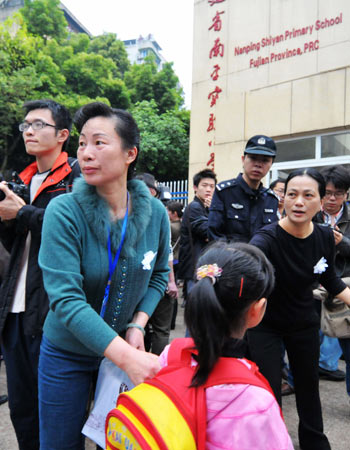 Teachers wait for the students at the gate of the Experimental School, where a knife attack occurred on Tuesday, in Nanping City, southeast China's Fujian Province, March 24, 2010. 