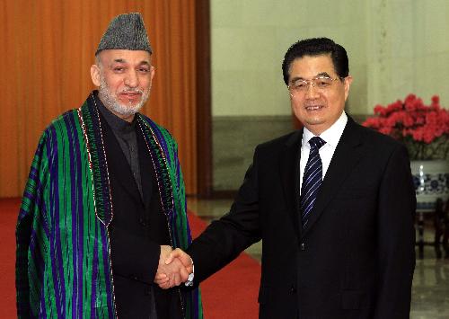 Chinese President Hu Jintao (R) shakes hands with visiting Afghan President Hamid Karzai in Beijing, capital of China, March 24, 2010. [Fan Rujun/Xinhua]