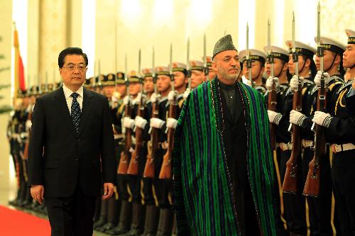 Chinese President Hu Jintao (L) and visiting Afghan President Hamid Karzai review the honor guard during a welcoming ceremony held for Karzai in Beijing, capital of China, March 24, 2010. [Fan Rujun/Xinhua]