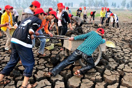 Young volunteers clear sludge at the bottom of the Chirui Lake at Shiping County, southwest China&apos;s Yunnan Province, March 24, 2010. The local government took the present opportunity of sustaining severe drought, which began to ravage the region since last autumn, to clear sludge of the lake. [Xinhua]
