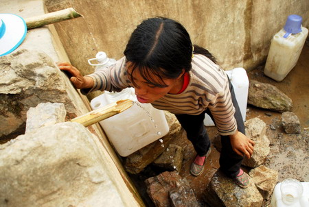  A woman standing in a nearly dried-up cistern tries to drink from the fountain in Luoping county, southwest China&apos;s Yunnan province, on March 24, 2010. The local government and people are struggling against the severe drought, which occurs once in 80 years, and the affected population is expected to reach tens of millions by May this year.[Xinhua]