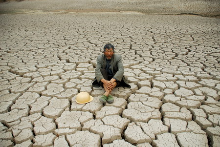 An old man sits on a dried-up reservoir in Jiulong town of Luoping county, southwest China&apos;s Yunnan province, on March 24, 2010. The local government and people are struggling against the severe drought, which occurs once in 80 years, and the affected population in Yunnan is expected to reach tens of millions by May this year.[Xinhua] 
