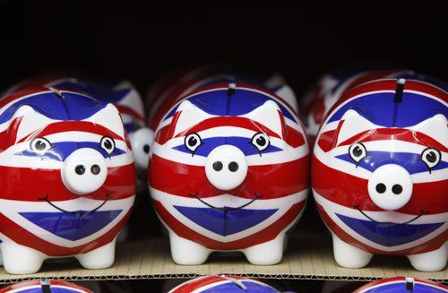  A row of piggy banks adorned with the colours of Britain&apos;s Union Jack flag are displayed in a souvenir shop in London March 24, 2010. [Xinhua/Reuters] 