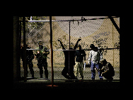 Military and forensic experts inspect the body of a man who was killed outside a nightclub in the border city of Ciudad Juarez August 31, 2009. A man was handcuffed to a fence and shot several times by drug hitmen outside a nightclub, according to local media. The assailants also left a warning message, known as 'narco mensaje', at the site of the shooting. REUTERS/Alejandro Bringas. [China Daily/CHIPP Organizing Committee] 