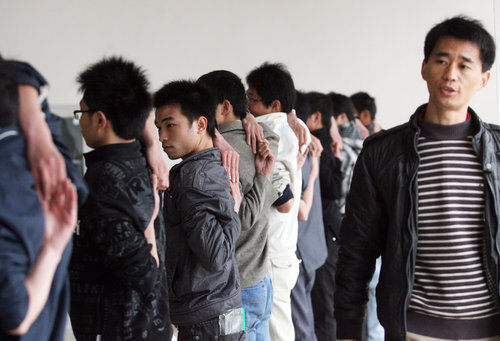 Students from Wuhan Institute of Shipbuilding Technology connect their hand from back to receive humpback test at a job fair held by Foxconn quasi-Precision Mold Co Ltd, in Wuhan, Hubei province, on March 23, 2010. 