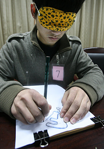 With eyes covered, a student from Wuhan Institute of Shipbuilding Technology is receiving a test of tracing irregular grooved lines on paper at a job fair held by Foxconn quasi-Precision Mold Co Ltd, in Wuhan, Hubei province, on March 23, 2010. 