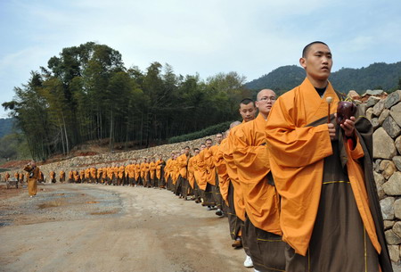 Buddhist monks walk towards tea bushes during a ceremongy before tea collecting, on the outskirts of Hangzhou, east China's Zhejiang province March 25, 2010. [Photo/Xinhua]
