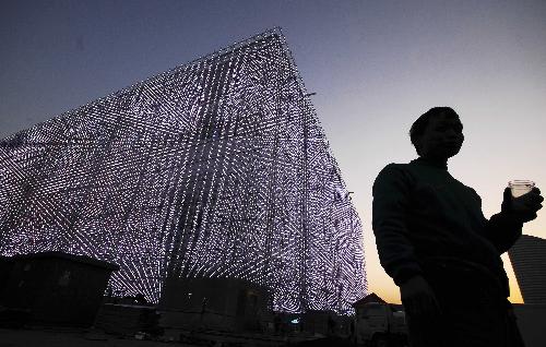 A man stands outside the Shanghai Corporate Pavilion on lighting trial at the Expo Park in Shanghai, east China, March 26, 2010. The Expo Park will be put into trial operation in the end of April.