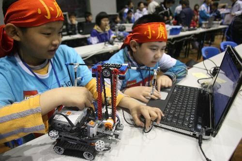 Two little contestants from the Beijing Delegation input the computer programme for the operation of their robot, during the China Open Match of the 2010 FLL Robot World Cup, which carries the theme of Intelligent Transport and draws over 1,000 contestants in 80 teams from 18 provinces and cities on mainland China and Hong Kong to take part in, at Jinan, east China's Shandong Province, March 27, 2010.