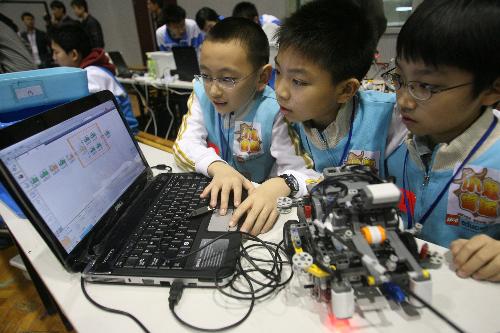 Three little contestants with the Beijing Delegation input the computer programme for the operation of their robot, during the China Open Match of the 2010 FLL Robot World Cup, which carries the theme of Intelligent Transport and draws over 1,000 contestants in 80 teams from 18 provinces and cities on mainland China and Hong Kong to take part in, at Jinan, east China's Shandong Province, March 27, 2010.