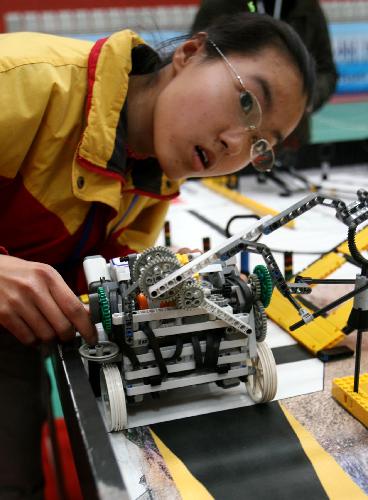 A contestant prepares for his robot adjustment, as the 2010 Suzhou Juvenile Robot Contest opens in Suzhou, east China's Jiangsu Province, March 27, 2010. Over 430 students take part in three levels of the contests in elementary school, junior and senior middle school, and categories of basic skills, robot football, robot basketball, etc.